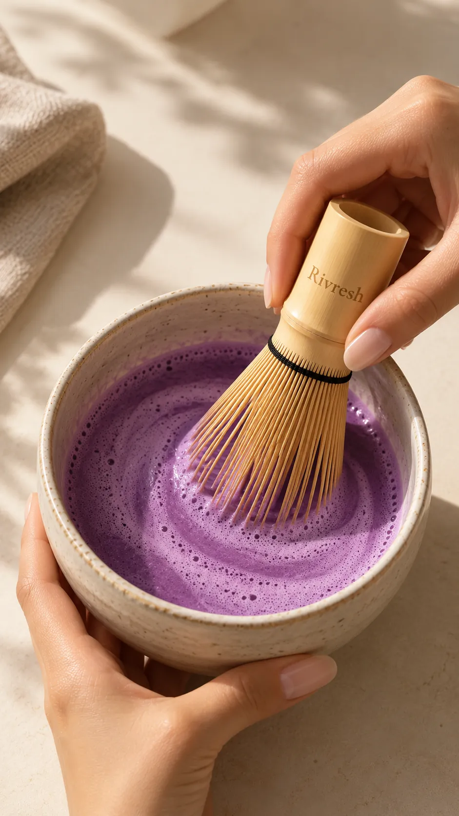 Handen kloppen paarse ube schuimig op in een stenen kom met de bamboe whisk met Rivresh-gravure.